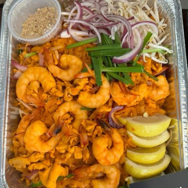 Delish Thai Kitchen's shrimp pad thai with bean sprouts, red onion, chives, and lemon wedges.