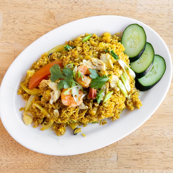 Delish Thai Kitchen's yellow curry fried rice with shrimp, chicken, vegetables, and cucumber slices.